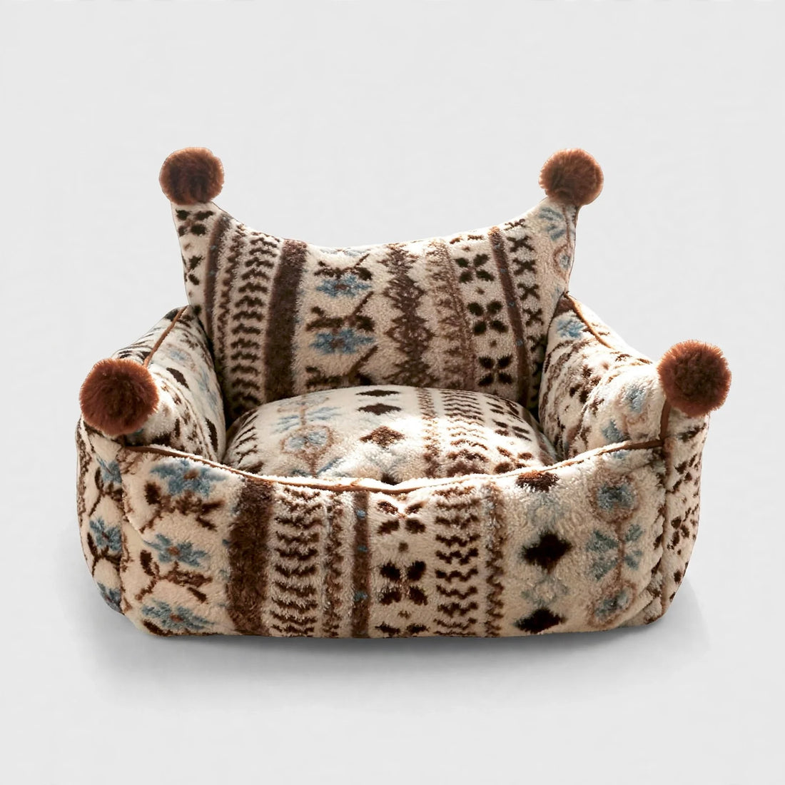 Patterned bolster pet bed with pom-pom corners on light background