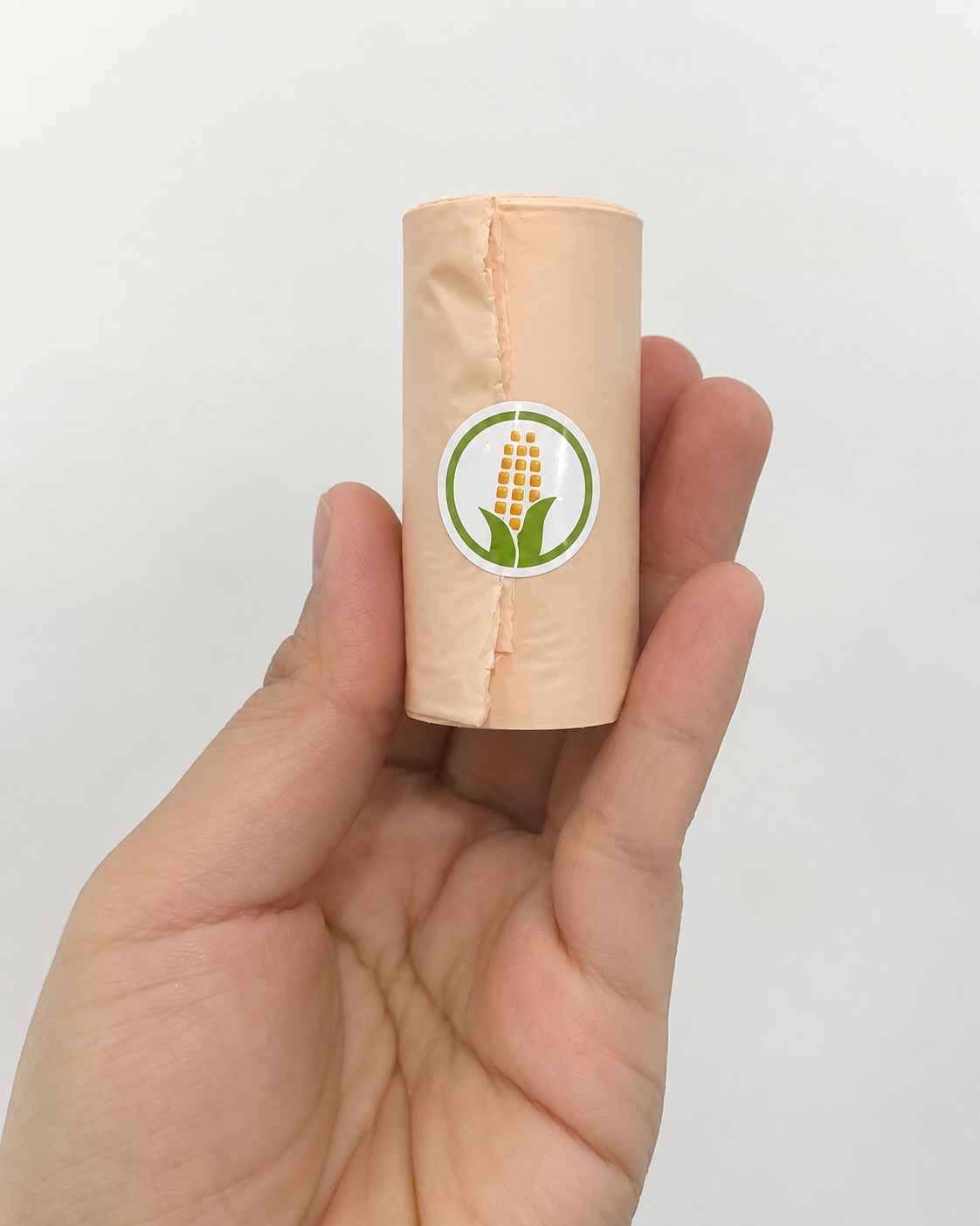 Beige biodegradable poop bag roll held in hand