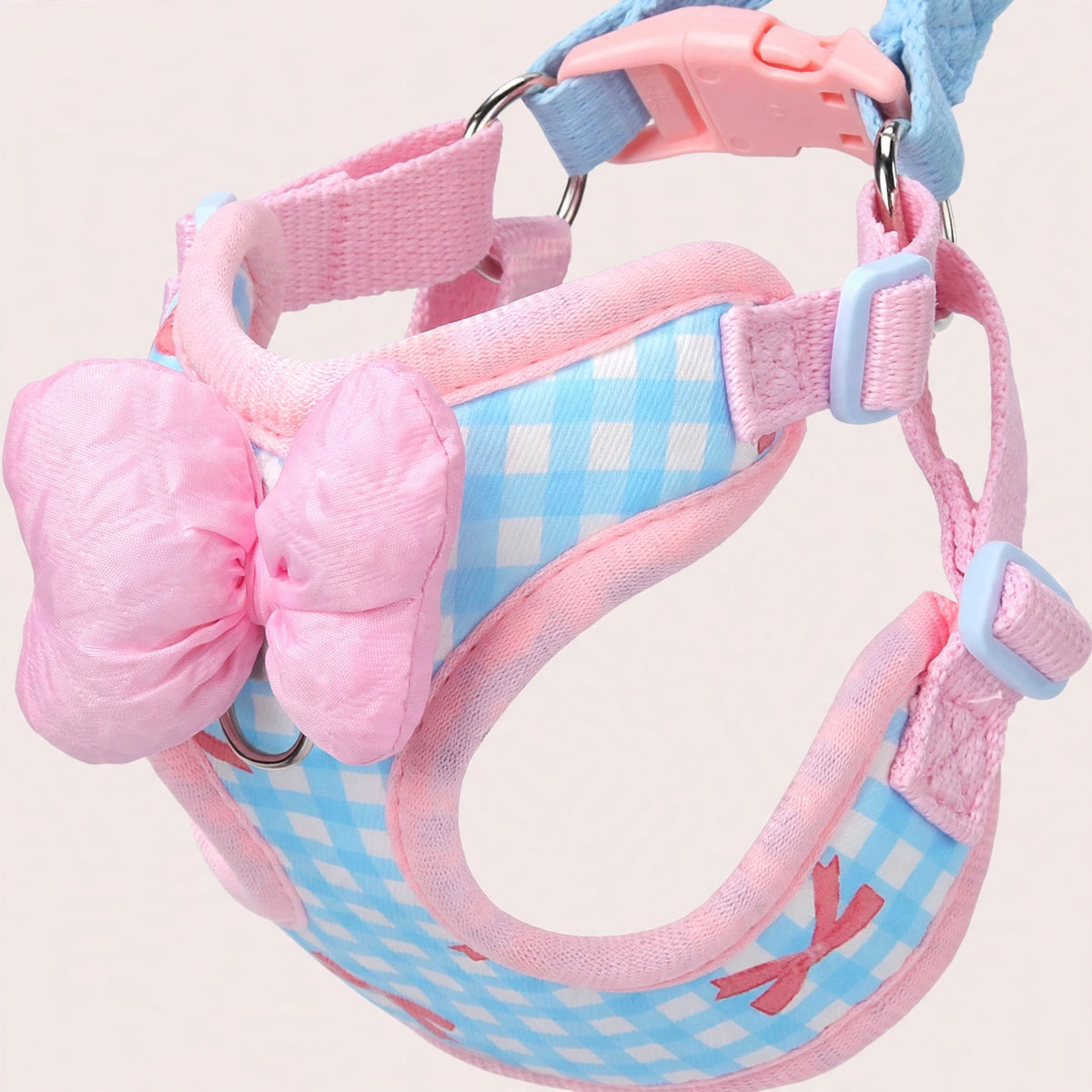 Close-up of pink bow and blue plaid fabric on small dog harness