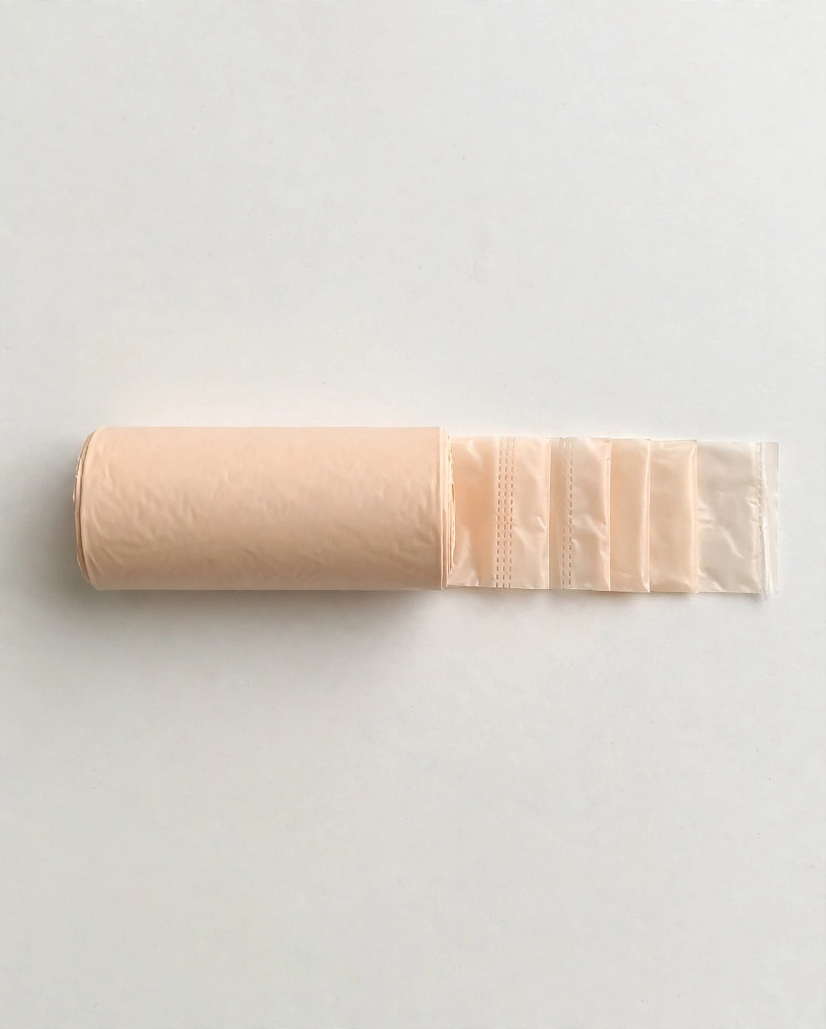Beige biodegradable poop bag roll with bags unrolled, flat lay