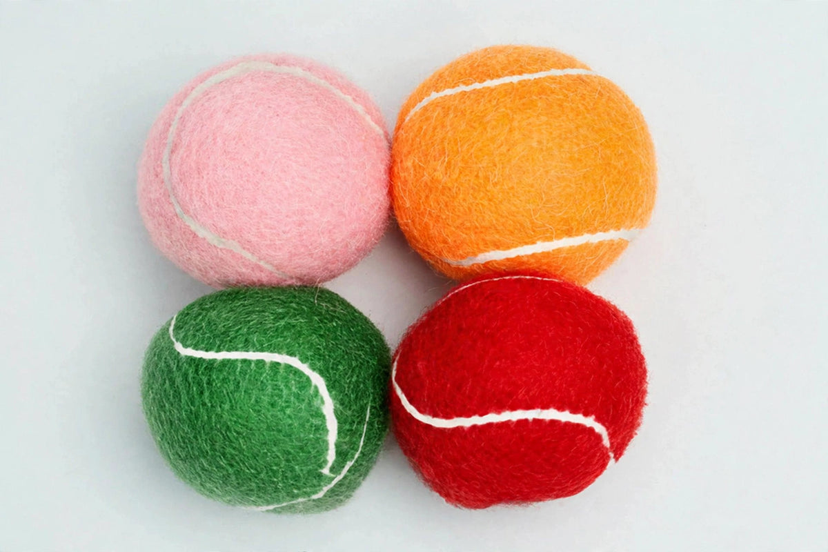 Close-up of four colorful squeaky tennis balls showing felt texture and seams
