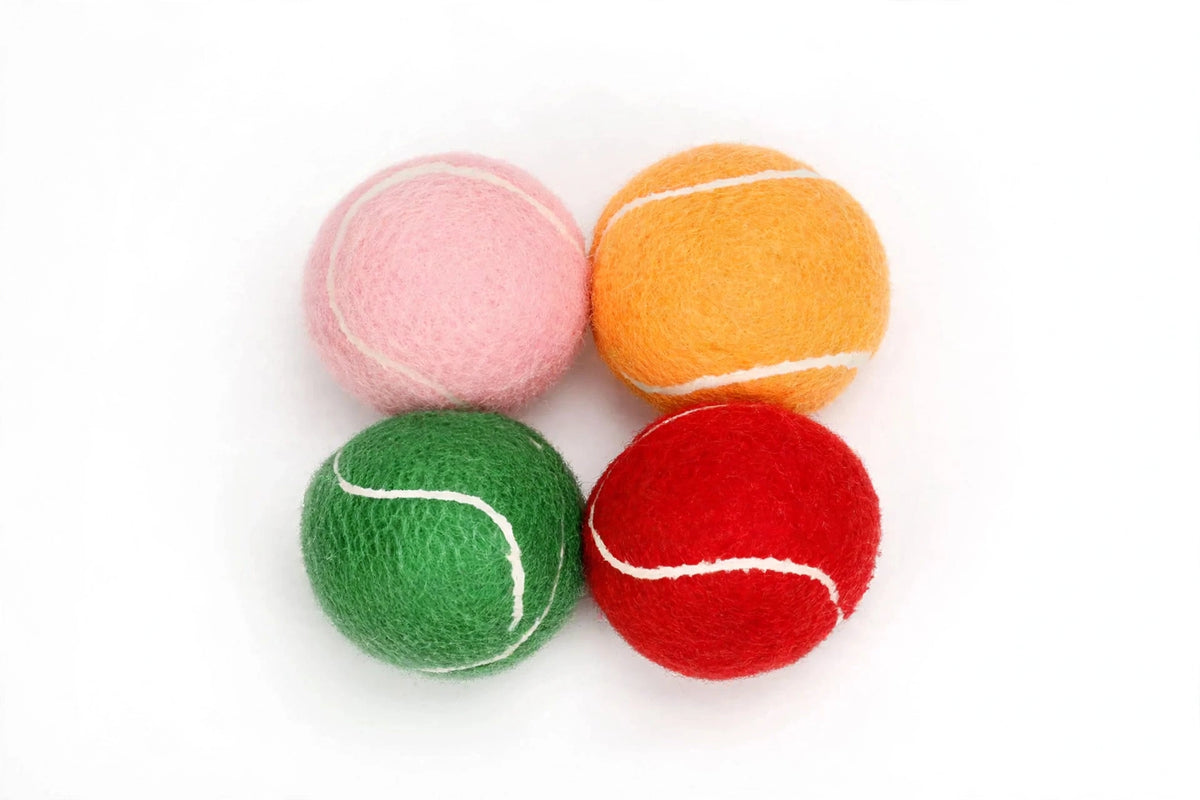 Four colorful squeaky tennis balls arranged on white background